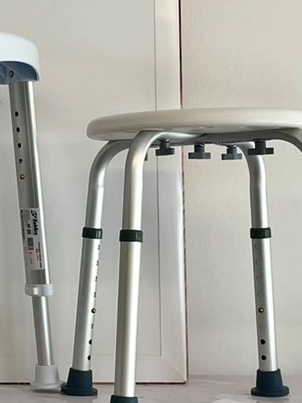 Sgabello da doccia con seduta tonda bianca e gambe in alluminio regolabili